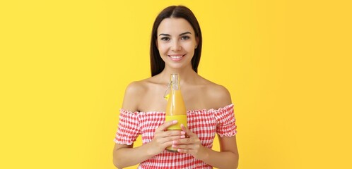 Wall Mural - Pretty young woman with healthy juice on yellow background