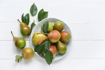 Wall Mural - Plate with ripe pears on white wooden table