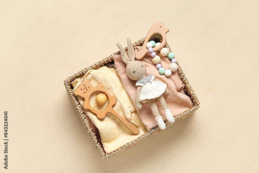 Wicker basket with gifts for baby on beige background