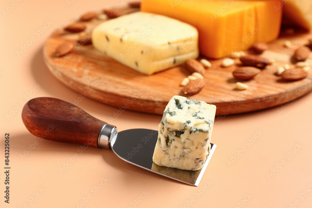 Knife with tasty cheese on beige background