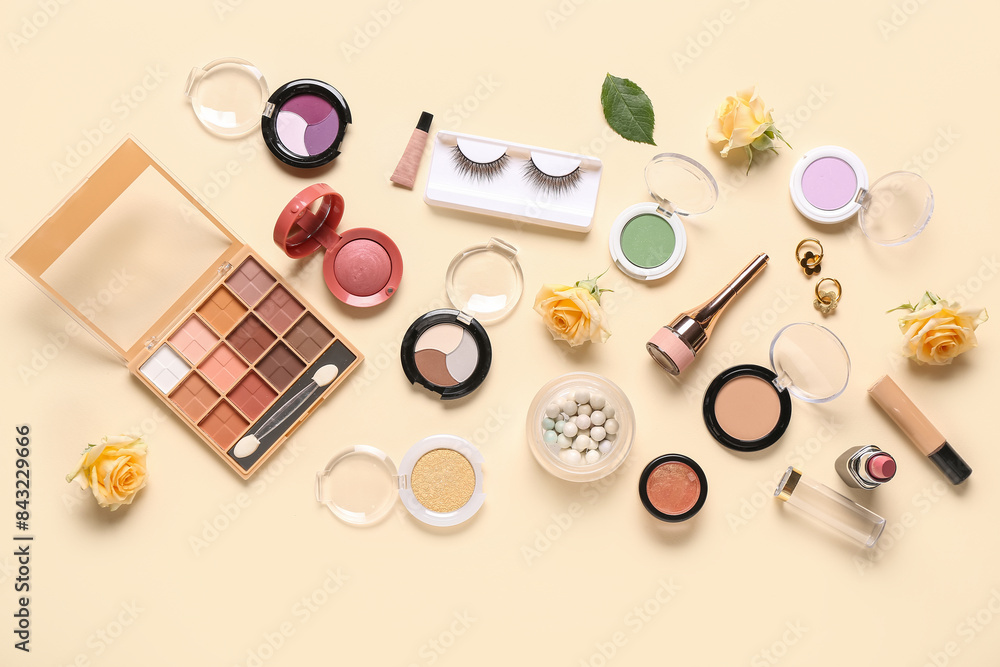 Makeup products with earrings and roses on beige background