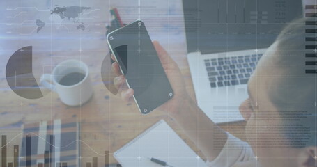 Canvas Print - Image of financial graphs over caucasian businesswoman holding smartphone with copy space