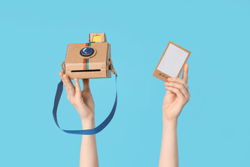 Female hands with paper instant photo camera and photo on blue background