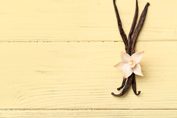 Wall Mural - Beautiful vanilla flower and sticks on yellow wooden background