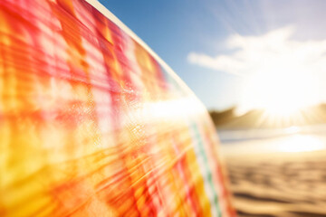 Wall Mural - A brightly colored surfboard leans against the warm sand on a beach at sunset. The sky is ablaze with orange and pink hues. Perfect for summer vibes, surfing content, or beach vacations.