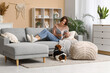 © Pixel-Shot - Young woman reading magazine and adorable Beagle dog sitting on floor at home
