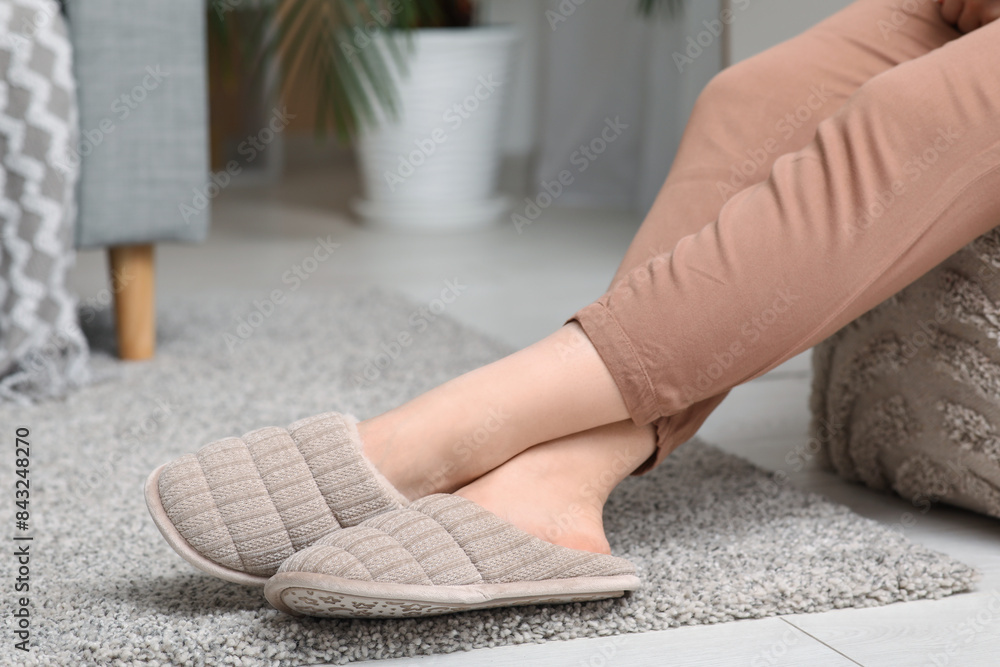Female legs in comfortable slippers in living room