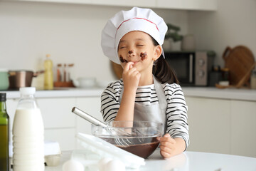 Sticker - Funny little Asian girl eating melted chocolate in kitchen