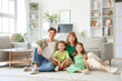 © Pixel-Shot - Happy parents with their little children sitting on floor at home