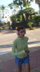 Wall Mural - Young Woman Jogging in a Tropical Urban Setting with Headphones, enjoying a healthy lifestyle