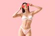 © Pixel-Shot - Young woman in silk underwear with paper hearts blowing kiss on pink background