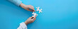 © jex - Two hands of business people connecting puzzle pieces on a blue background with copy space, symbolizing collaboration and teamwork. Background for business solutions, success, and strategy.