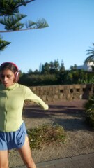 Wall Mural - Woman jogging with headphones in a park, staying active and enhancing her wellness and fitness