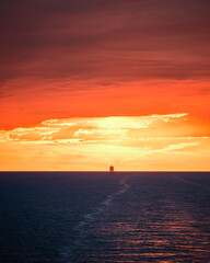 Sticker - A large ship silhouetted on the horizon of the Mediterranean sea against a dramatic orange sunset