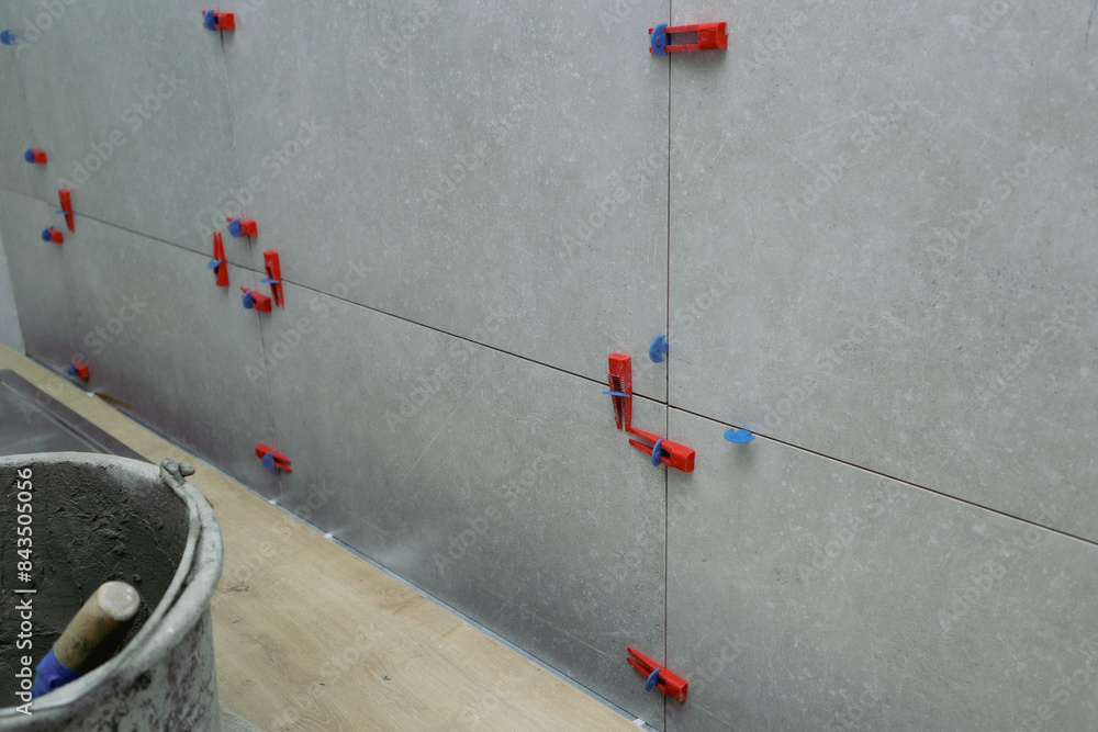 Installation of porcelain tiles on the wall. Tile leveling system. Modern system for leveling tiles during installation.