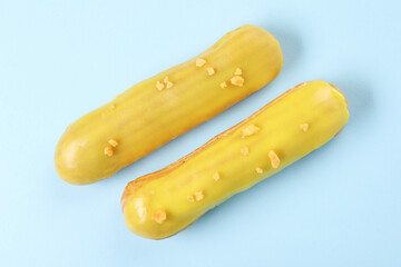 Poster - Delicious eclairs covered with glaze on light blue background, top view