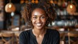 © Tetiana - A young woman with curly hair smiles at the camera while sitting at a restaurant table