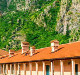 landscape of beautiful vintage houses with orange tile roofs in vintage venetian style to amazing high green mountain with ancient buildings on slopes and nice cloudy sky on background