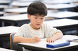 © kapinon - An elementary school boy studying and holding a pencil during class in a classroom