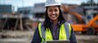 © Gular - Mixed race female engineer happily works on a construction site holding a digital tablet and smiling at the camera in a waist up portrait The image allows for copy space