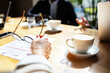 © Marko Geber - Close-up of hand holding glasses with coffee and documents on the table during a business meeting