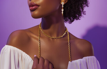 A model wearing a gold chain link bracelet, necklace and earrings with a white top on a purple background