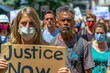 © AiHRG Design - A crowd of people, wearing face masks, participate in a peaceful demonstration, holding signs and demanding justice.