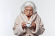 © Anna - grumpy old woman in bathrobe holding cup of coffee Isolated on white background