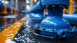 © familymedia - Close-up of a blue industrial valve with water droplets, part of a complex piping system