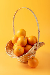 Wall Mural - Fresh oranges in basket on a orange background.