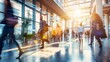 © Thanaphon - Busy modern office hallway with people walking, sunlight streaming in, creating a dynamic and energetic workplace environment.