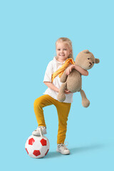 Wall Mural - Cute little girl with soccer ball and teddy bear on blue background