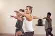© EmilLL/peopleimages.com - Woman, warrior pose and instructor in yoga class, balance and exercise together for peace in studio. Female person, pilates and coach training a group of people, stretching and yogi for wellness