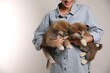 © New Africa - Woman holding Akita Inu puppies on light background, closeup. Space for text