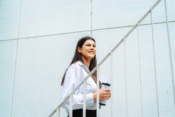 One young successful business woman going to work at business office modern building while holding coffee and papers	