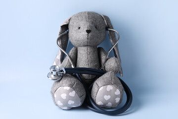 Wall Mural - Toy bunny with stethoscope on light blue background