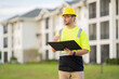© Panacea Stock  - A man in a yellow safety vest is looking at a tablet while wearing a hard hat. He is focused on the device, possibly checking for safety information or instructions