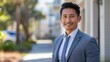 © Distinctive Images - **Professional Asian businessman in blue suit smiling outdoors, corporate lifestyle portrait in urban setting**