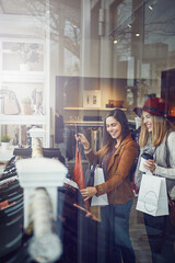 Women, customer and happy with dress in boutique store for promotion, discount and sale. Smile, female friends and people checking rack of clothes in fabric, material and retail shop at indoor mall