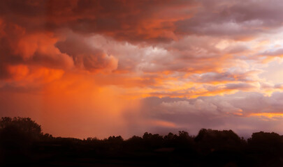 Colorful sunset sky with storm clouds over the town to create beautiful nature light in background.