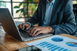 © Fahima - A professional businessman working on a laptop computer with financial data charts and graphs