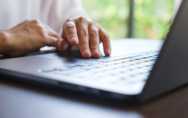 Closeup image of a woman hand working and touching on laptop computer touchpad