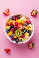 Bowl of healthy fresh fruit salad on pink background, top view