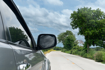 Wall Mural - Grey car driving on the upcountry concrete road with trees and green grass. Under blue sky and white clouds. Going forward to travel with nature in Thailand.