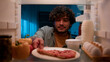 © Yuliia - View inside from refrigerator Indian sly man with curly hair open fridge at night evening in kitchen hungry guy male looking around take out slice of pizza overeating at nighttime unhealthy nutrition