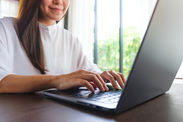 Wall Mural - closeup image of a woman working and typing on laptop computer keyboard