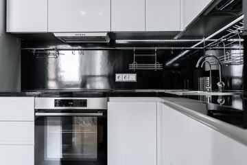 Wall Mural - modern minimalist black and white kitchen.  Kitchen with built-in kitchen appliances, microwave, oven, refrigerator. The countertop and dining area in the kitchen are made of black stone.