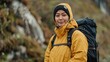 © Leli - A woman wearing a yellow jacket and a black hat hikes near a waterfall