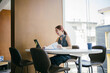 © Parichat - Young Professional Woman Working on Laptop in Modern Office Space with Documents and Coffee