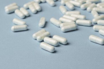 Wall Mural - White capsules on a blue background. Vitamins and dietary supplements concept